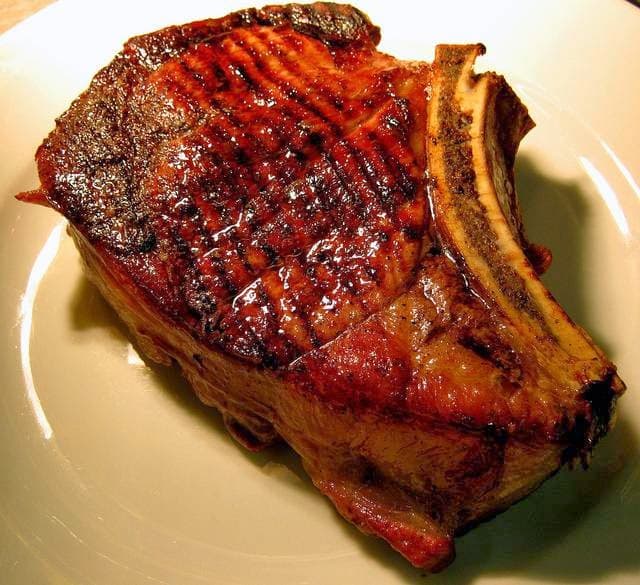 Juicy, grilled steak with a charred exterior, served on a white plate.