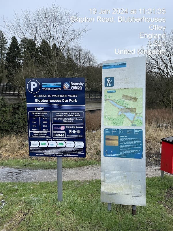 Blubberhouses Car Park sign with parking information and tariff details, surrounded by grass and trees in Yorkshire.