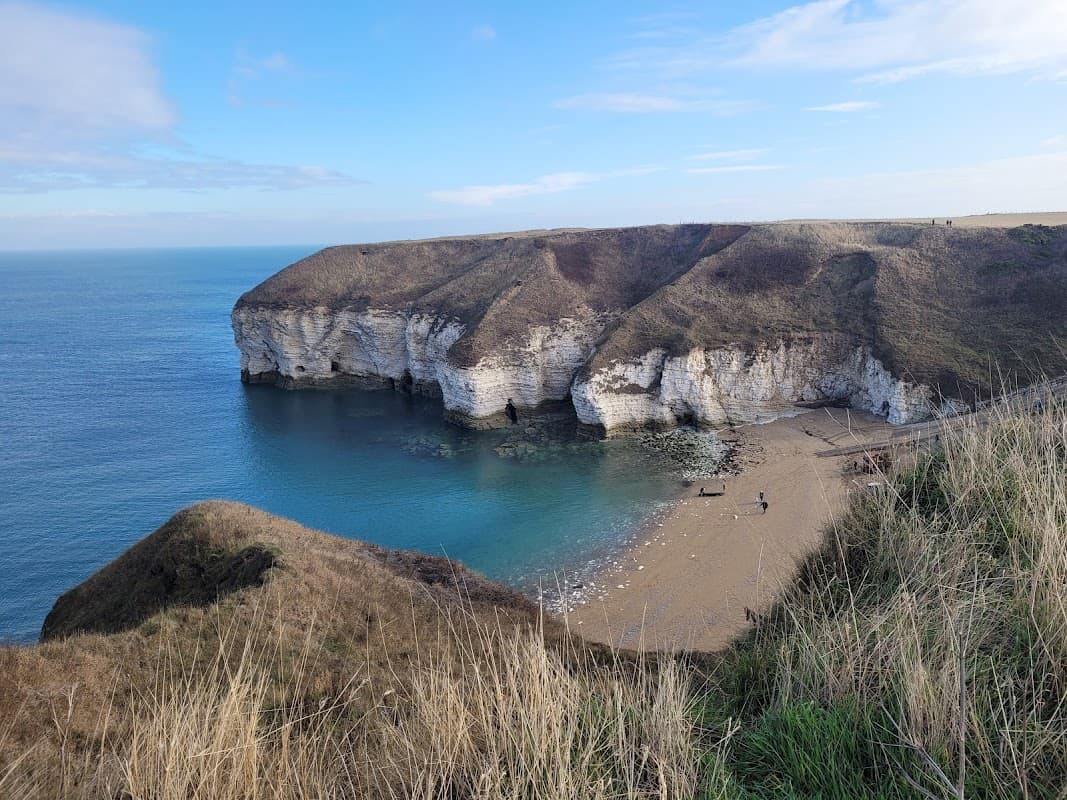 Scenic view of North Landing with cliffs, sandy beach, and calm blue sea under a clear sky in Flamborough, Yorkshire.