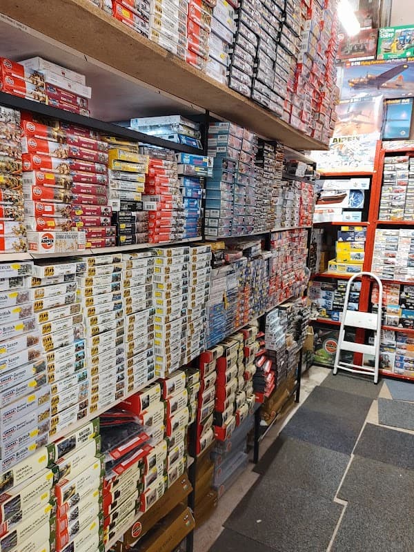 A narrow aisle lined with shelves stacked high with model kits and boxes in a well-organized store.