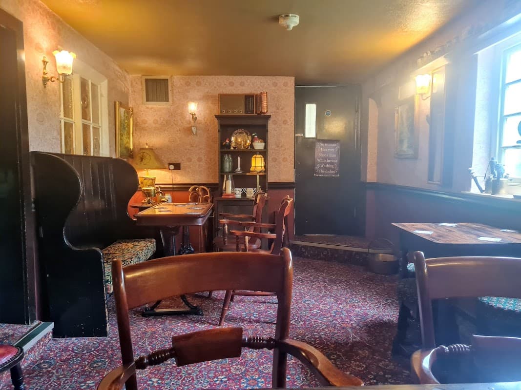 Cozy bar interior with patterned wallpaper, wooden tables, chairs, and a welcoming atmosphere in Follifoot, Yorkshire.