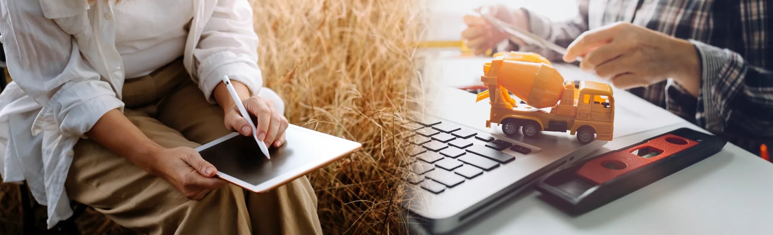 A person writes on a tablet beside a toy cement mixer and a laptop with a level tool on a desk.