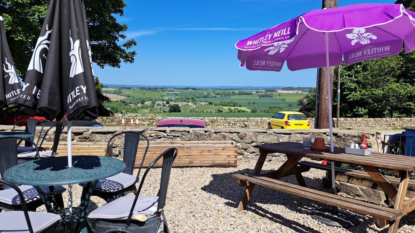 Outdoor seating area with tables, umbrellas, and scenic views of rolling hills in North Yorkshire.