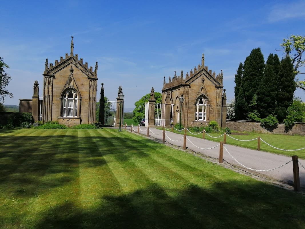 Gisburne Park Lodge features ornate stone buildings, manicured lawns, and a clear blue sky in Yorkshire.