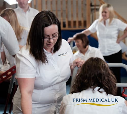 Staff in white shirts collaborate in a bright, open space, focusing on equipment at Prism Medical UK in Grange Moor.