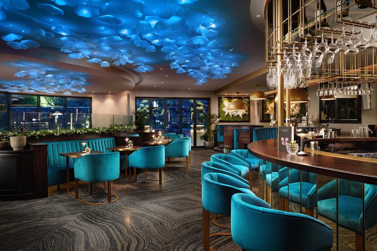 Stylish interior of Restaurant EightyEight with blue ceiling decor, elegant bar, and plush teal seating.