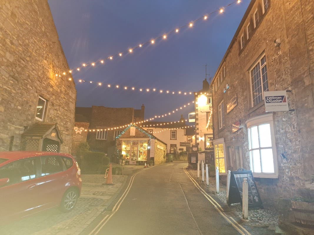 Twinkling lights adorn a charming street in Grassington, with stone buildings and a cozy atmosphere at dusk.