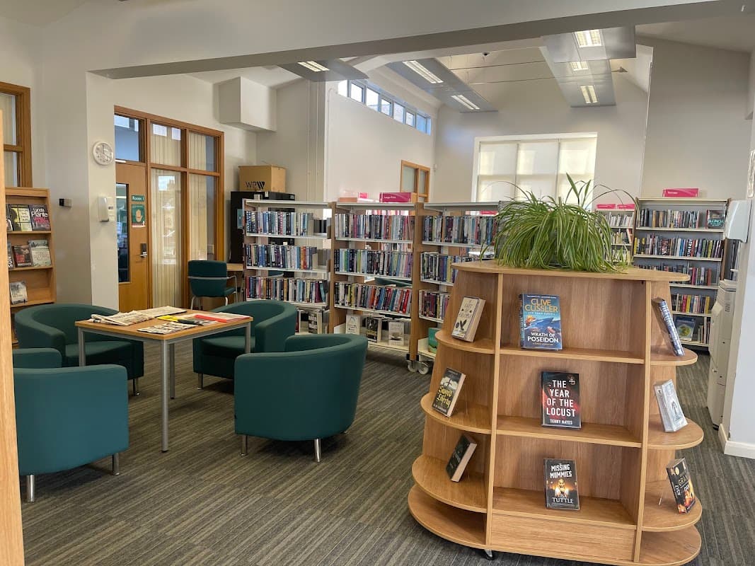 Bright interior of Driffield Library with bookshelves, seating area, and a wooden display stand for books.