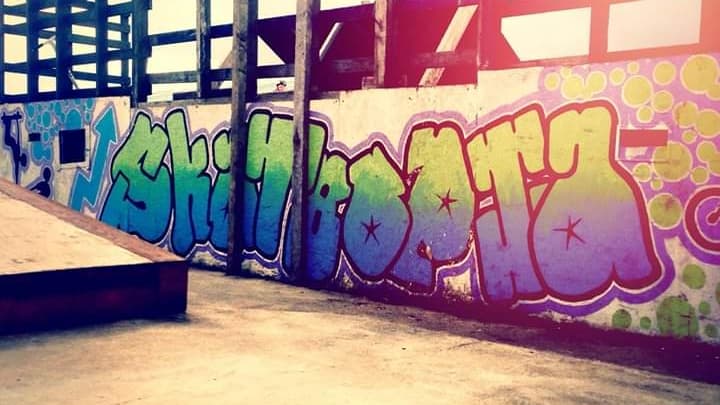 Colorful graffiti spelling "Skateopia" on a wall at Driffield Skate Park, with a wooden ramp in the foreground.