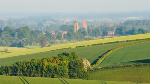 Lush green fields with distant buildings and church towers under a clear blue sky in Great Driffield, Yorkshire.