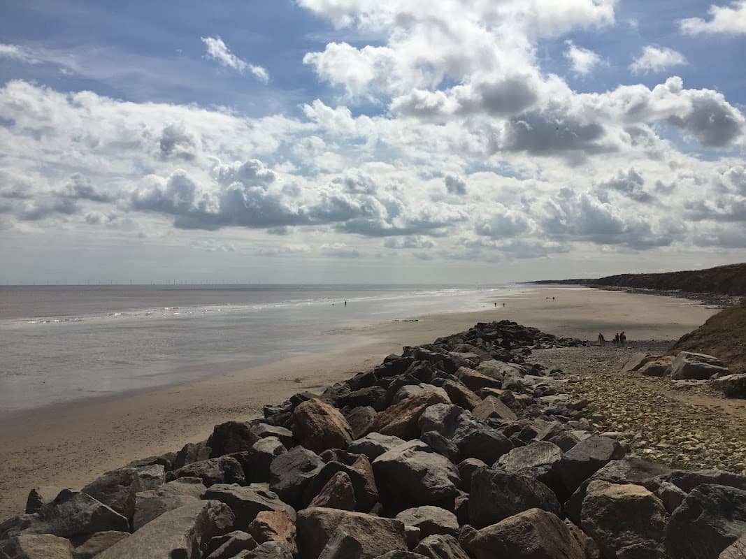 Scenic beach view with rocky shoreline, gentle waves, and cloudy sky in Great Hatfield, Yorkshire.