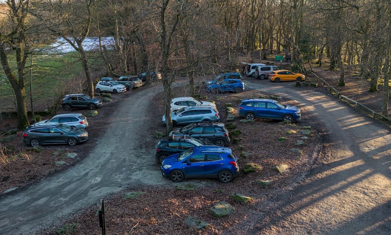 Pay & Display car park surrounded by bare trees, featuring various parked cars on a gravel surface in Grenoside, Yorkshire.