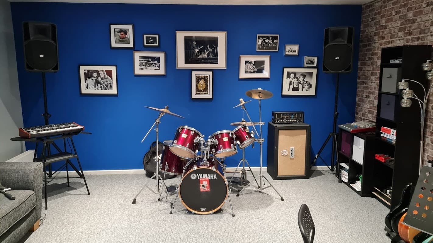 Drum set, keyboard, framed music photos, speakers, and a cozy music studio in Hade Edge, Yorkshire.