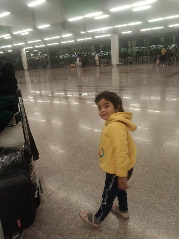 A child in a yellow hoodie walks through a spacious, well-lit car park with polished floors.