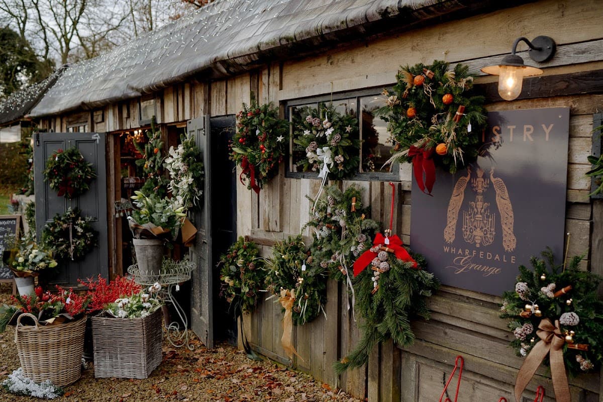 Charming floristry shop with festive wreaths, greenery, and seasonal decorations adorning wooden doors and walls.
