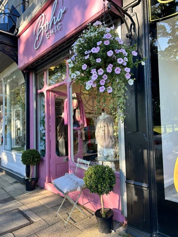 Pink storefront with "Boho Chic" sign, hanging flower basket, and topiary plants outside the shop in Harrogate.