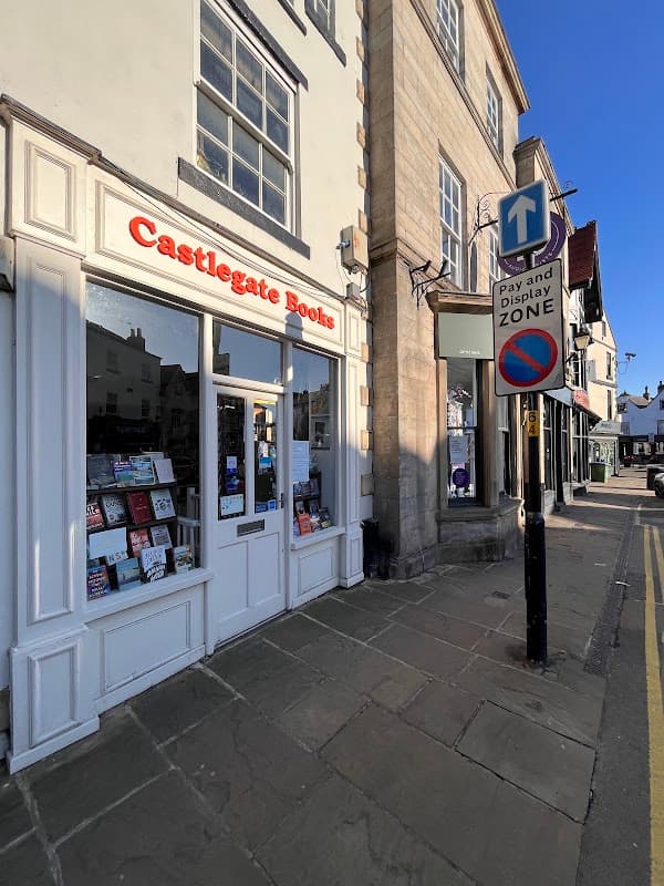 Castlegate Books storefront with books displayed, beside a street sign indicating a pay and display zone.
