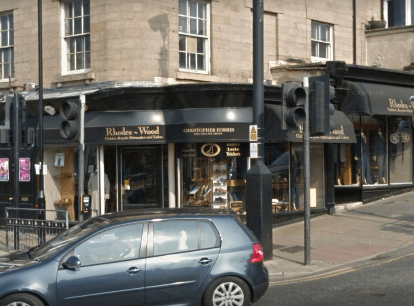 Rhodes-Wood shoe shop exterior in Harrogate, featuring a sign with "Christopher Forbes" and parked car in front.