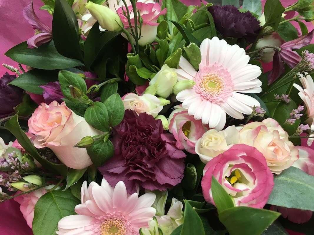 A vibrant bouquet featuring pink and white flowers, including gerberas, roses, and lush greenery.