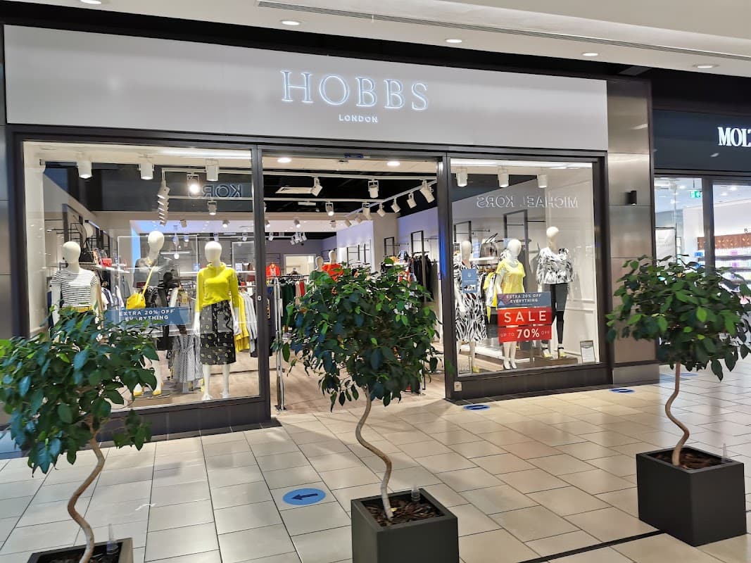 Hobbs store entrance with mannequins in stylish clothing and a 70% off sale sign, flanked by small potted trees.