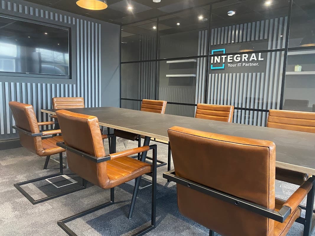 Modern conference room with a large black table, brown leather chairs, and a glass wall displaying the "INTEGRAL" logo.