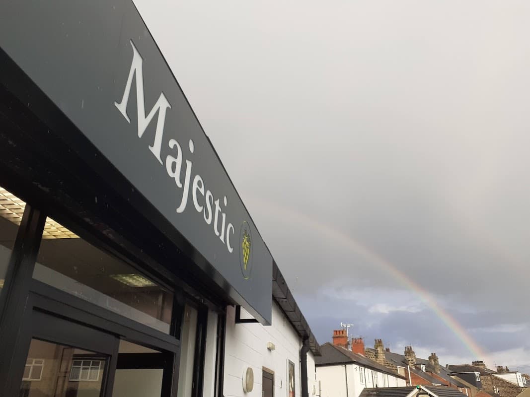 Sign for Majestic Wine with a rainbow in the cloudy sky above, showcasing a typical Harrogate street scene.