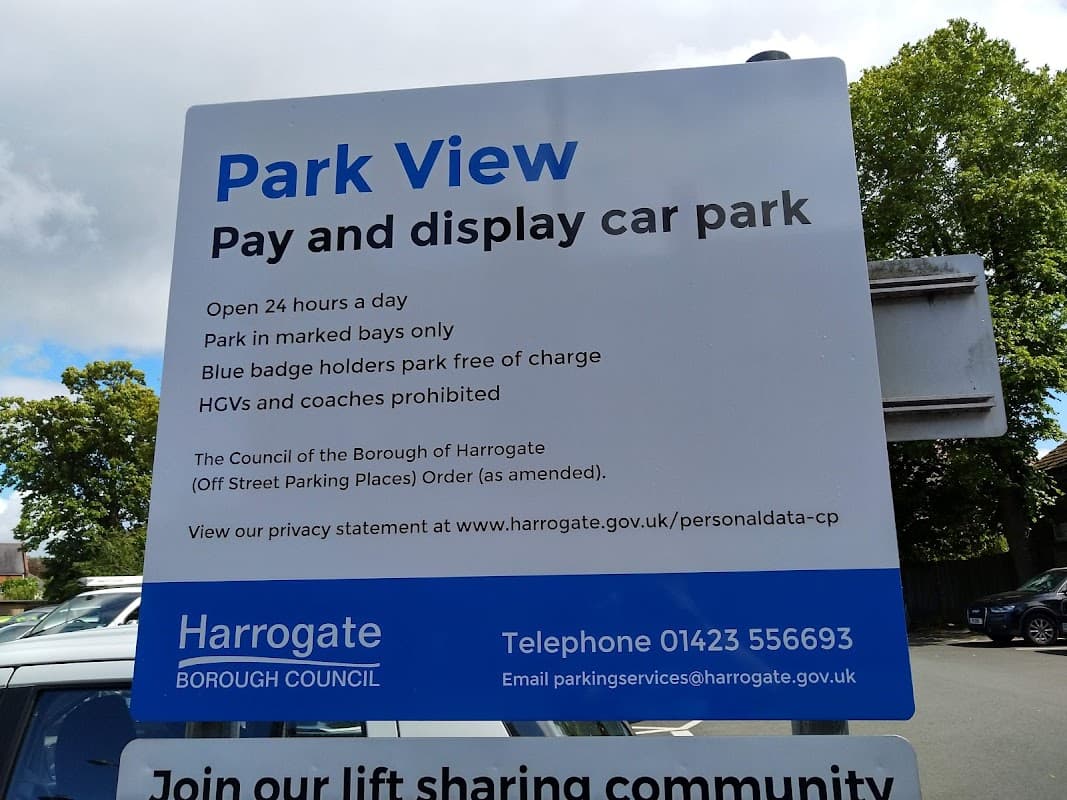 Sign for Park View car park in Harrogate, detailing parking rules and contact information. Trees in the background.