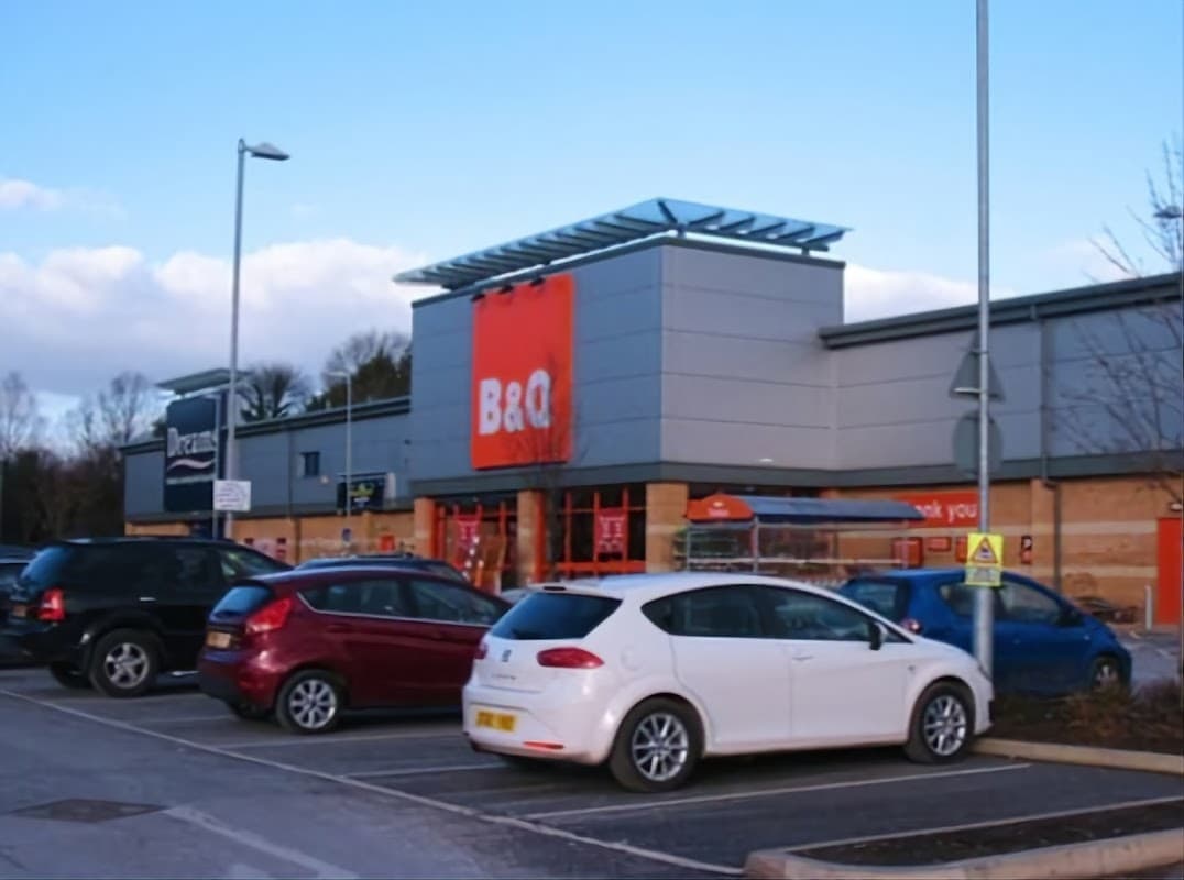 B&Q store exterior with parking lot, featuring various cars and a clear blue sky in Harrogate, Yorkshire.