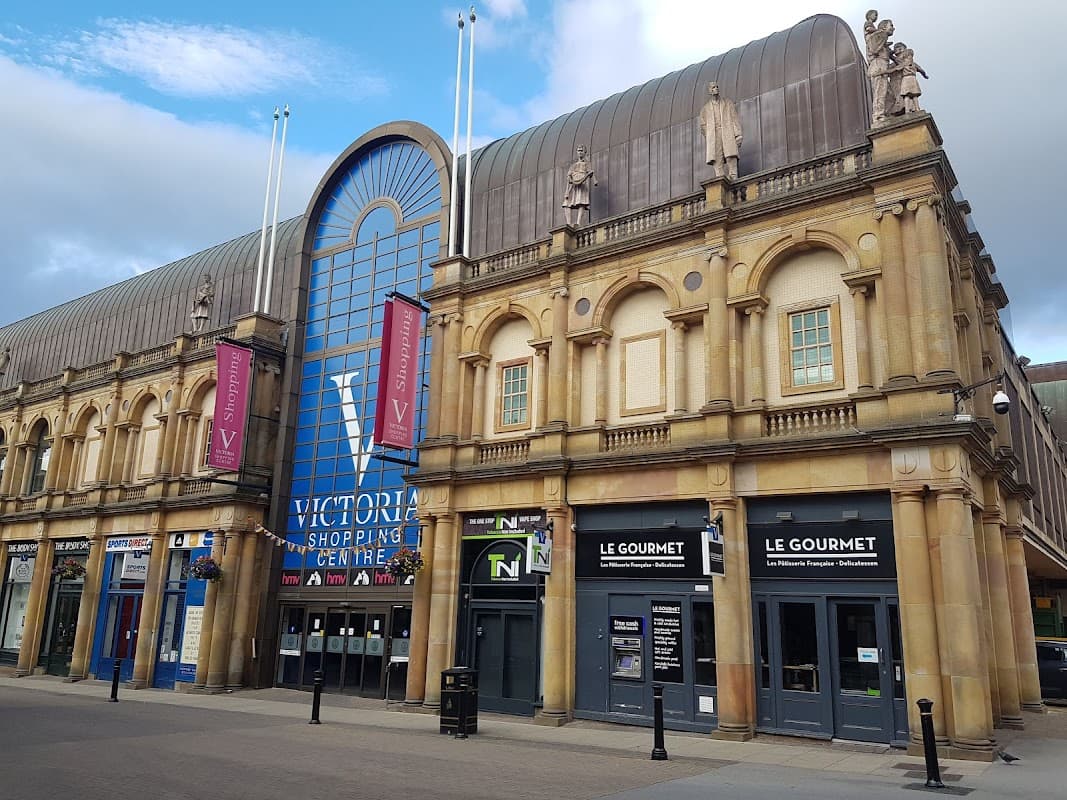 Historic architecture of Victoria Shopping Centre featuring large blue entrance and storefronts with signage.