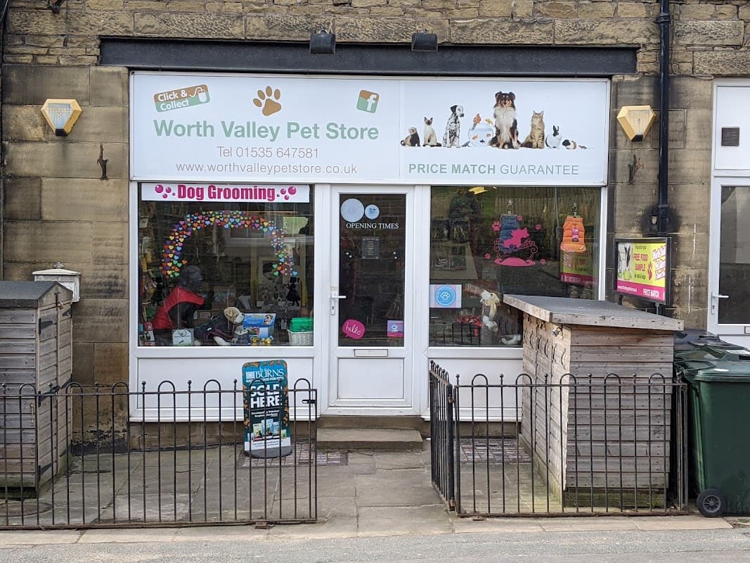 Pet shop storefront featuring colorful signage, dog grooming service, and a fenced entrance in Haworth, Yorkshire.