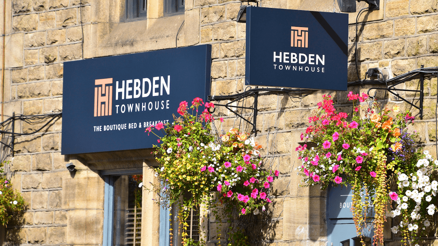 Signage for Hebden Townhouse, a boutique bed and breakfast, adorned with colorful flower baskets.
