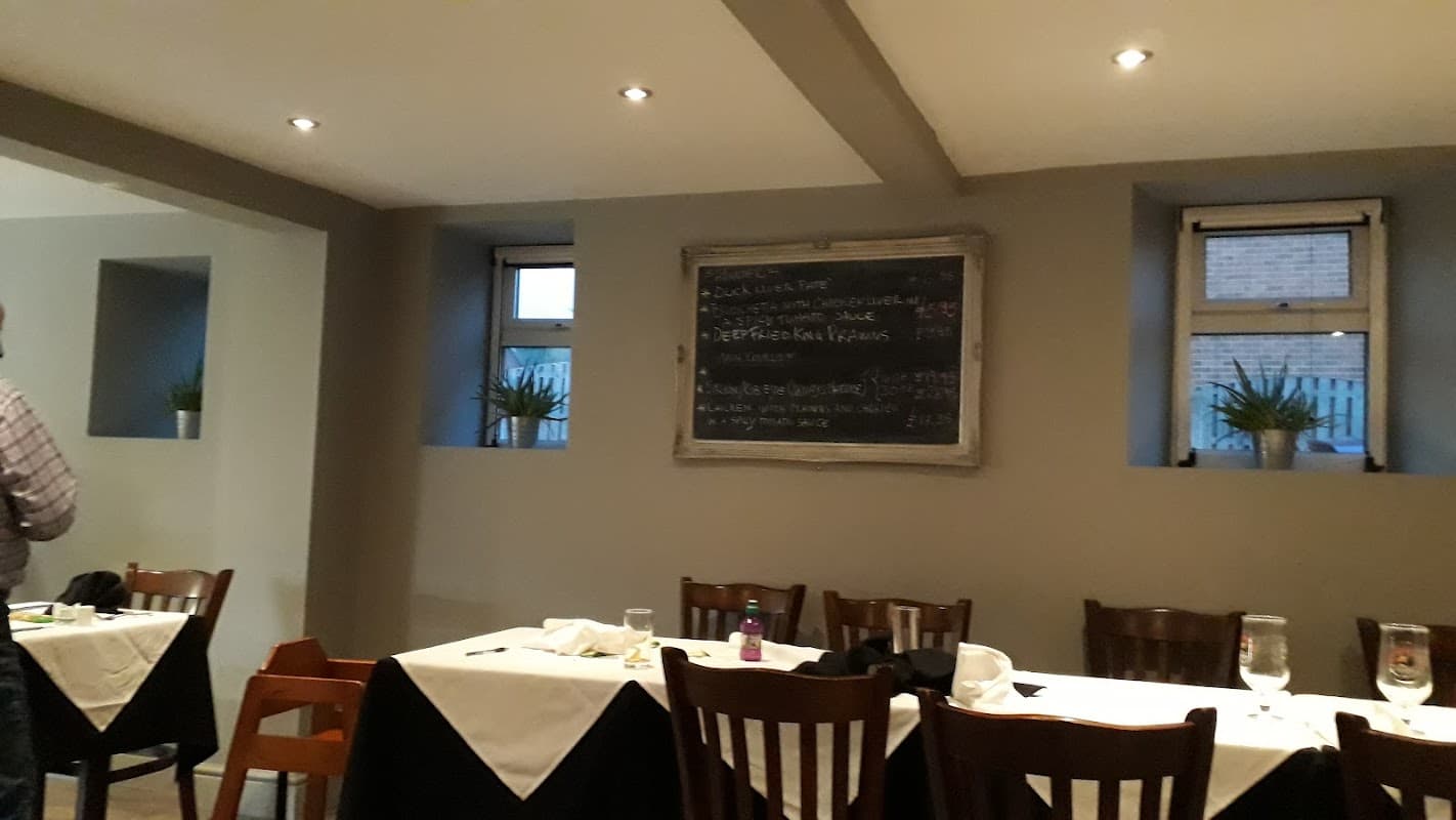 Interior of La Anchor with wooden tables, a chalkboard menu, and potted plants by the windows.