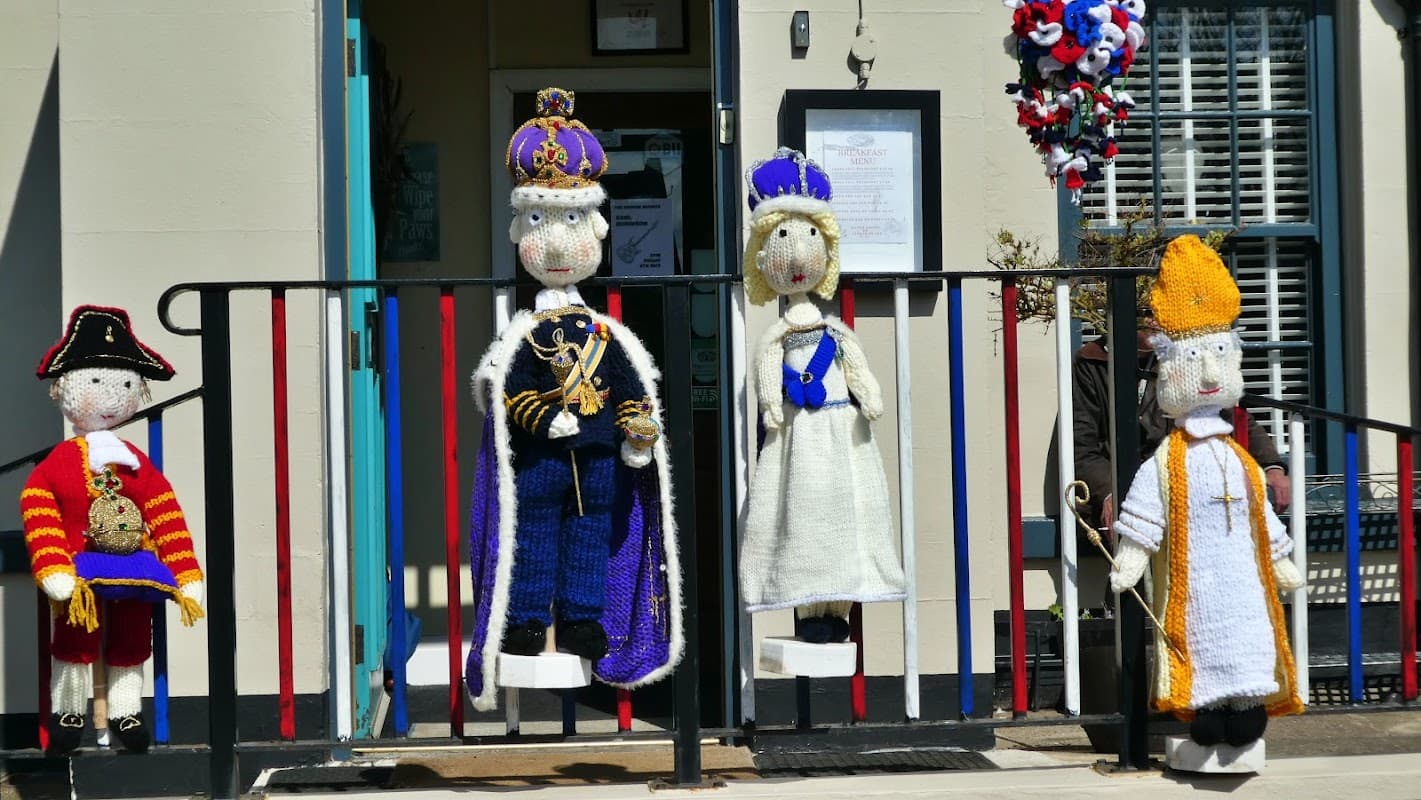 Four colorful yarn figures dressed as royalty and a pirate stand outside The Badger Hounds restaurant in Hinderwell.