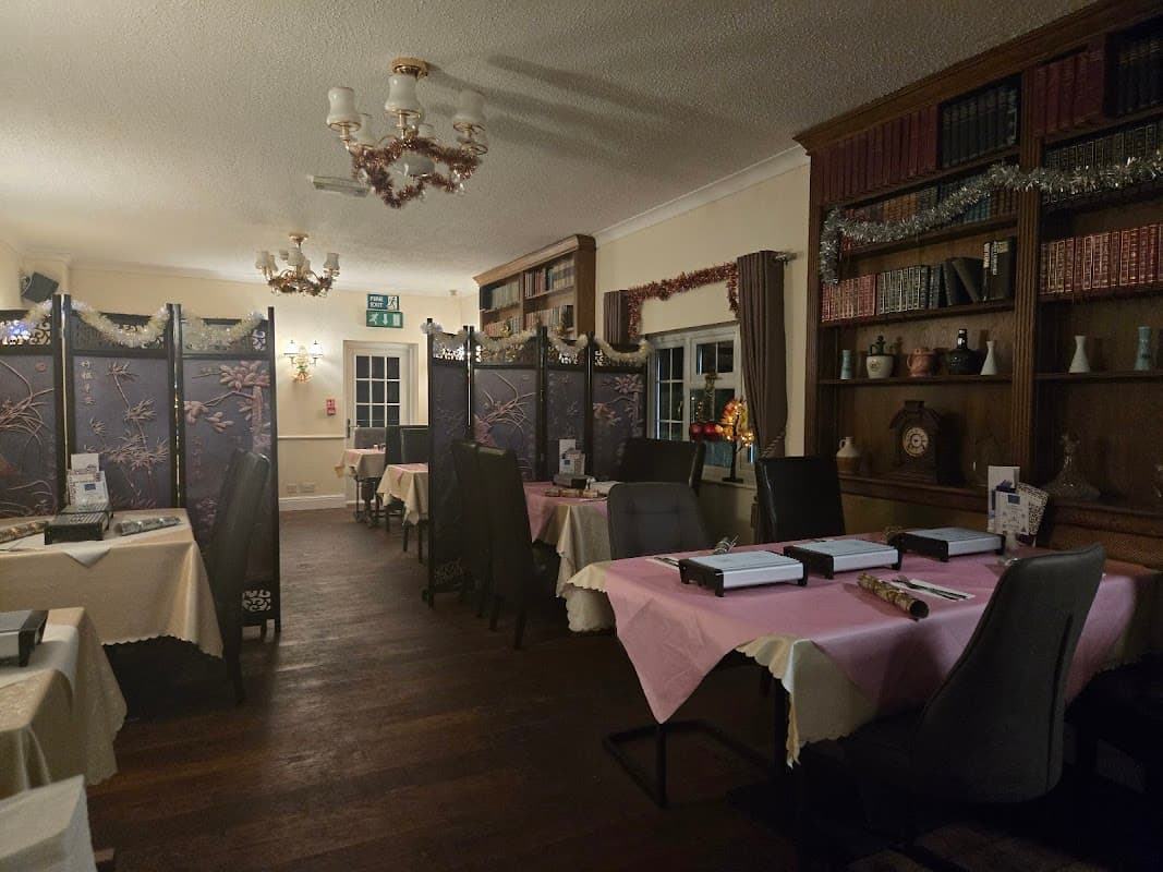 Cozy dining area with pink tablecloths, wooden bookshelves, and decorative screens in a warm, inviting atmosphere.