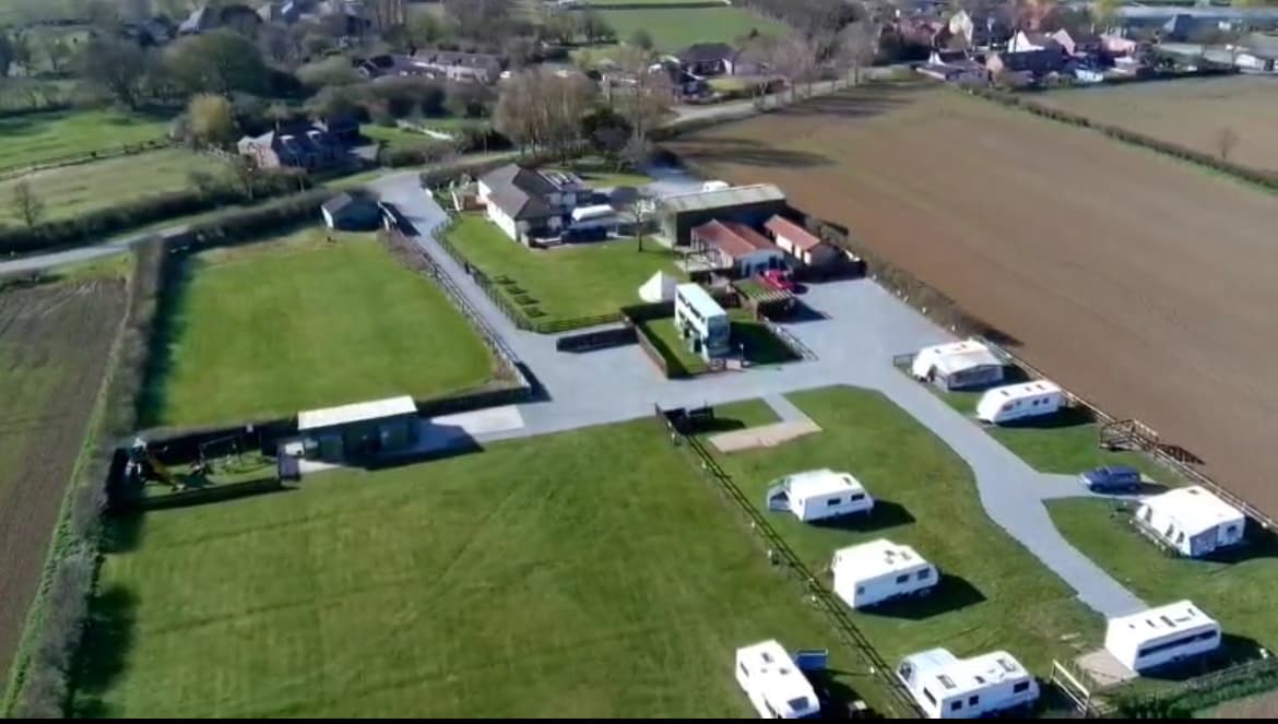 Aerial view of Hollym Holiday Park featuring caravans, green fields, and surrounding residential areas in Holmpton, Yorkshire.