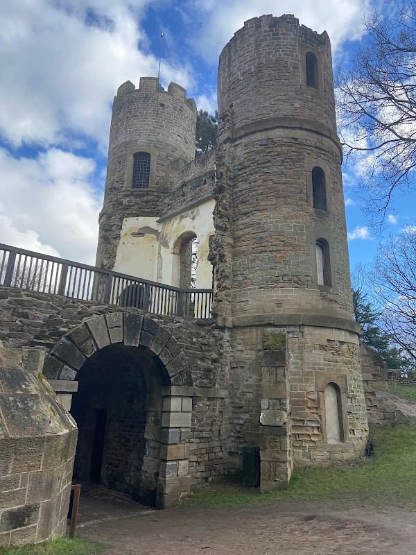 Ruins of Stainborough Castle with stone towers and archways, set against a blue sky with scattered clouds.