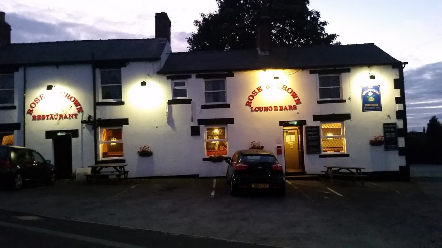 The Rose & Crown bar with illuminated signage, parked cars, and a cozy exterior in Hoylandswaine, Yorkshire.