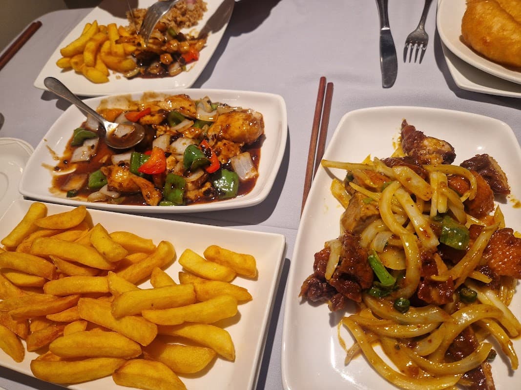 Two plates of Cantonese dishes with chicken and vegetables, accompanied by a serving of golden fries.