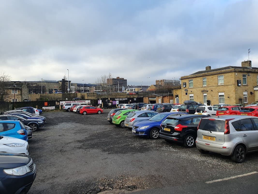 Aspley £4 Car Park filled with various parked cars, surrounded by buildings and a cloudy sky.