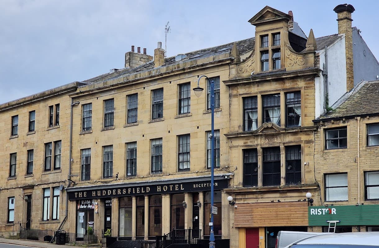 Huddersfield Hotel with a classic facade, large windows, and a sign for reception, set in a historic area.