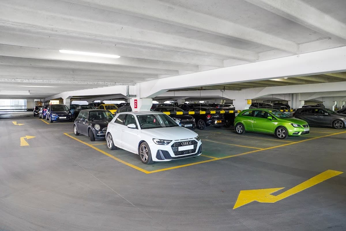 Multi-storey car park with parked cars, marked parking spaces, and directional arrows on the floor.