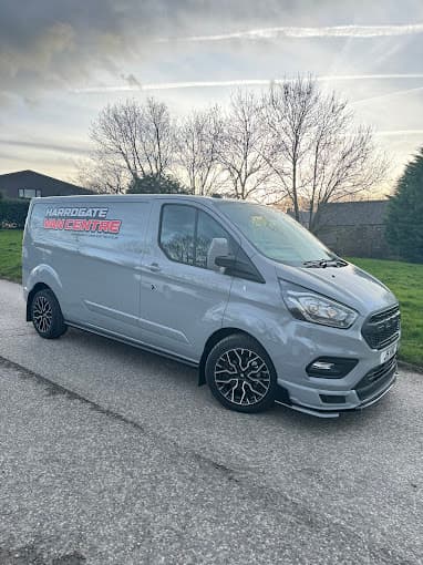 Silver van with "Harrogate Van Centre" branding parked on a road, surrounded by trees and a grassy area.