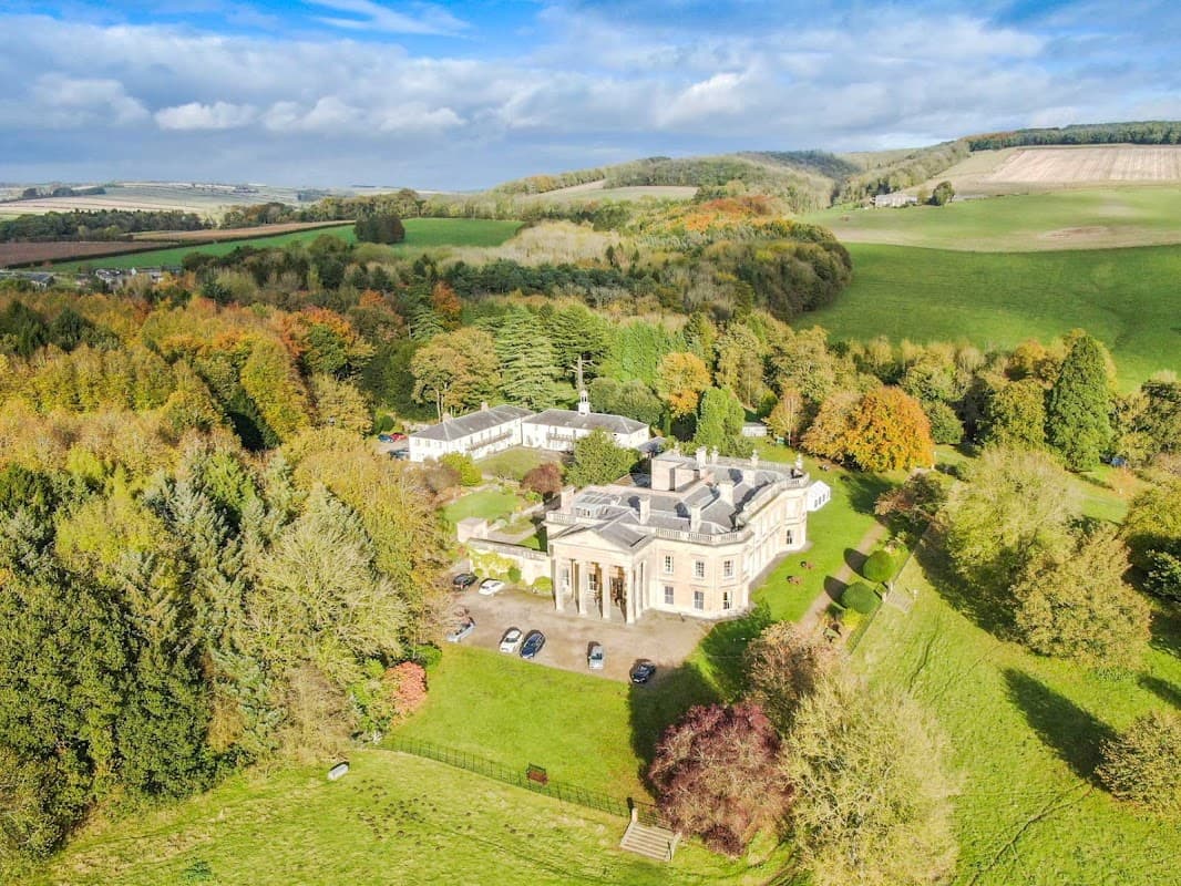 Aerial view of Madhyamaka Kadampa Meditation Centre surrounded by lush greenery and rolling hills in Yorkshire.