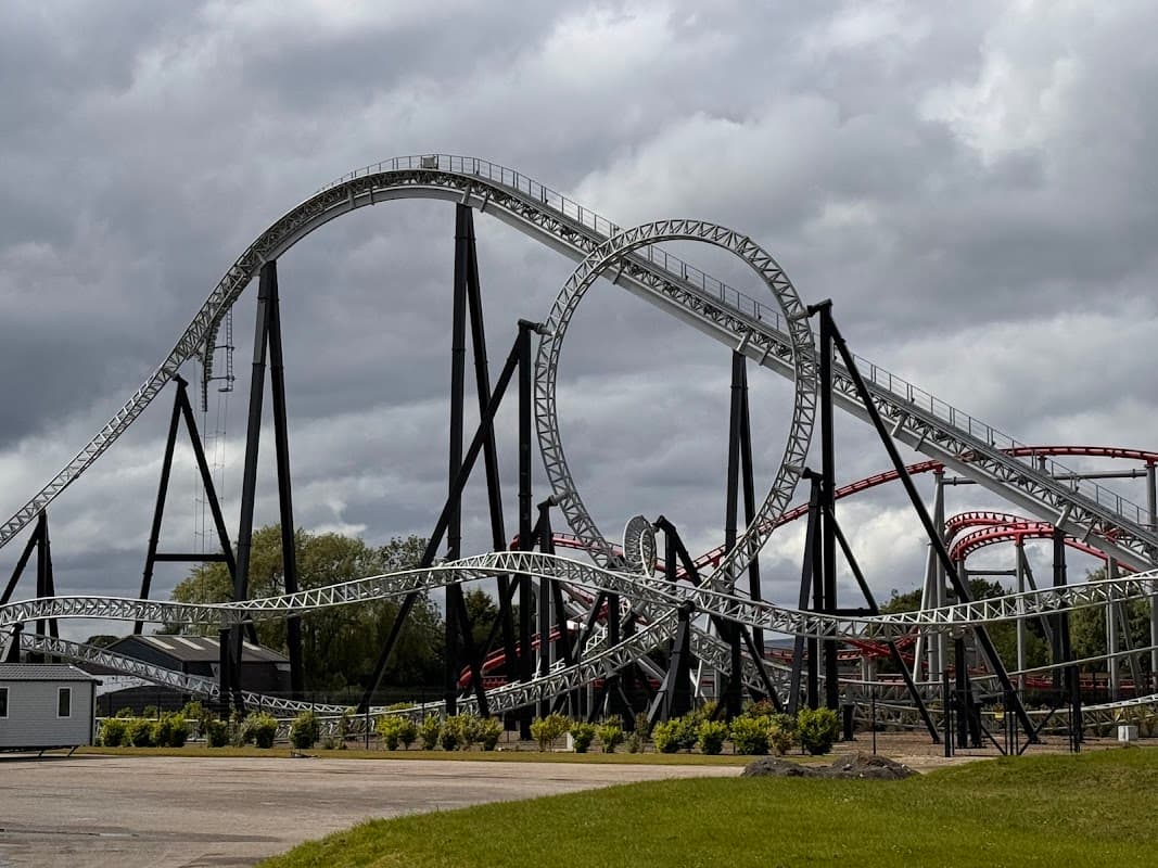 A large roller coaster with black and red tracks, featuring multiple loops, set against a cloudy sky in Kirby Misperton.