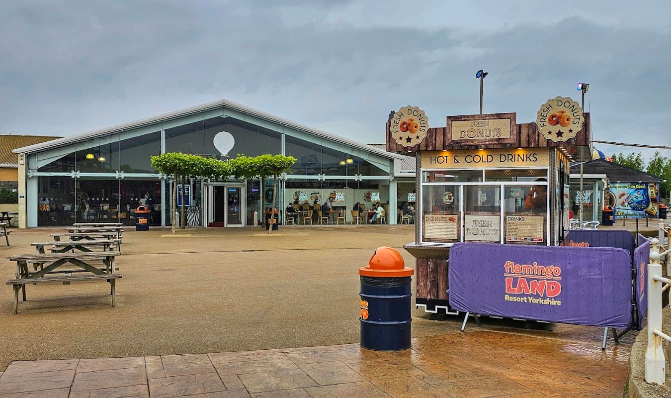 Event venue with a modern glass facade, outdoor seating, and a drinks stall in front.