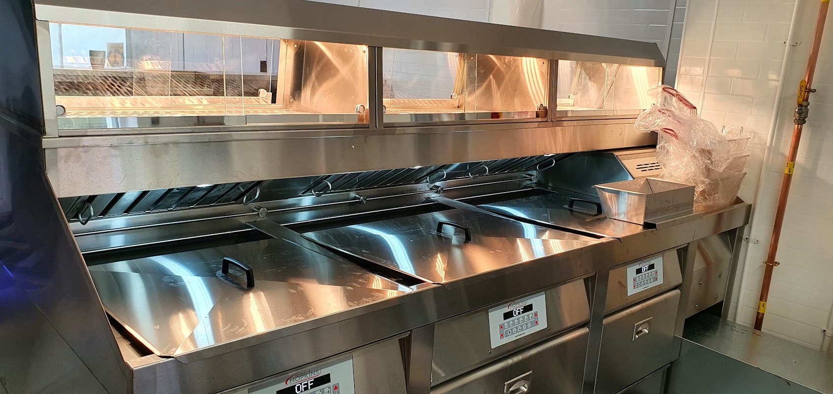 Stainless steel fish and chip fryer station with multiple fryers and a clean, organized workspace.