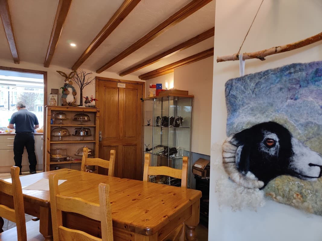 Cozy tea room interior with wooden beams, a dining table, and a decorative sheep portrait on the wall.