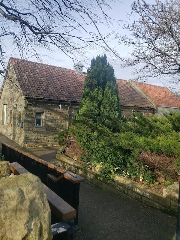 The Ley Hall features a stone building with a red-tiled roof, surrounded by lush greenery and trees in Lealholm.