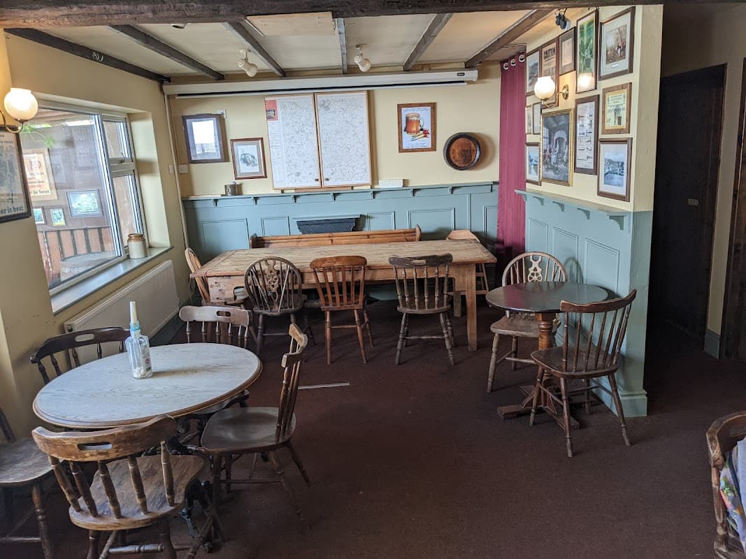 Cozy bar interior with wooden tables and chairs, framed pictures on the walls, and a large map on display.