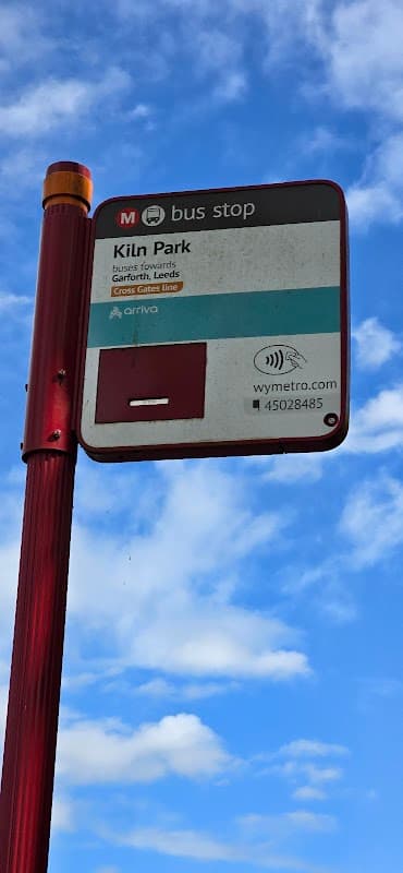 Bus stop sign for Kiln Park, with blue sky and clouds in the background, indicating routes to Garforth and Leeds.